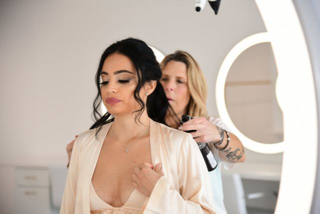 a woman is getting her hair done by a hairdresser in front of a mirror