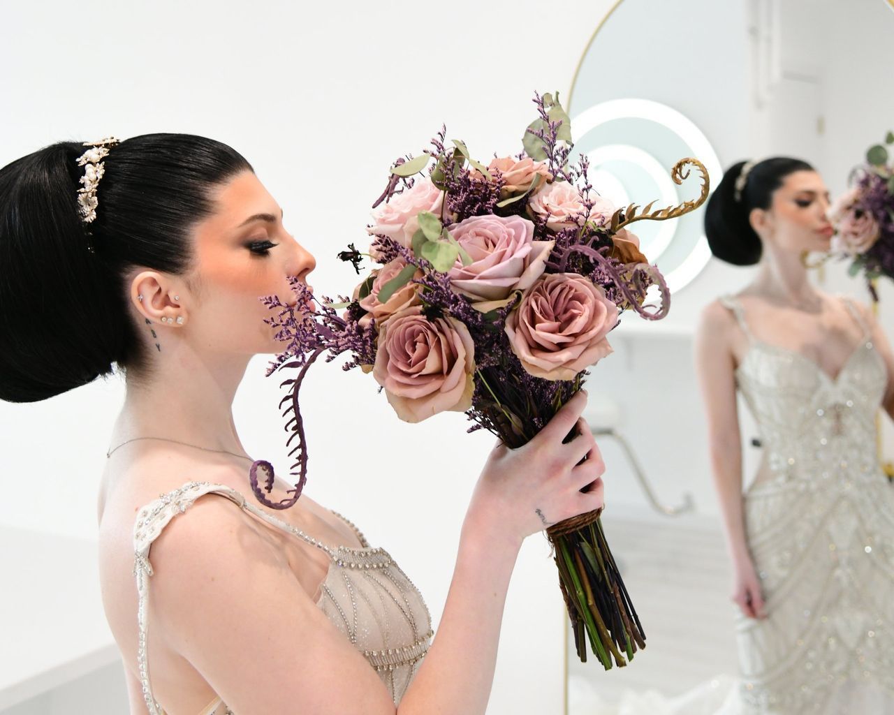 a woman in a wedding dress is holding a bouquet of flowers in front of a mirror