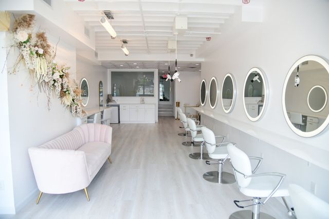 a salon with a pink couch and white chairs and mirrors