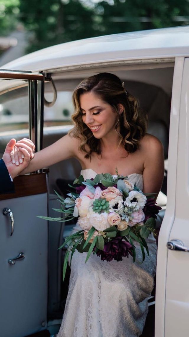 the bride is holding the hand of the groom while getting out of the car