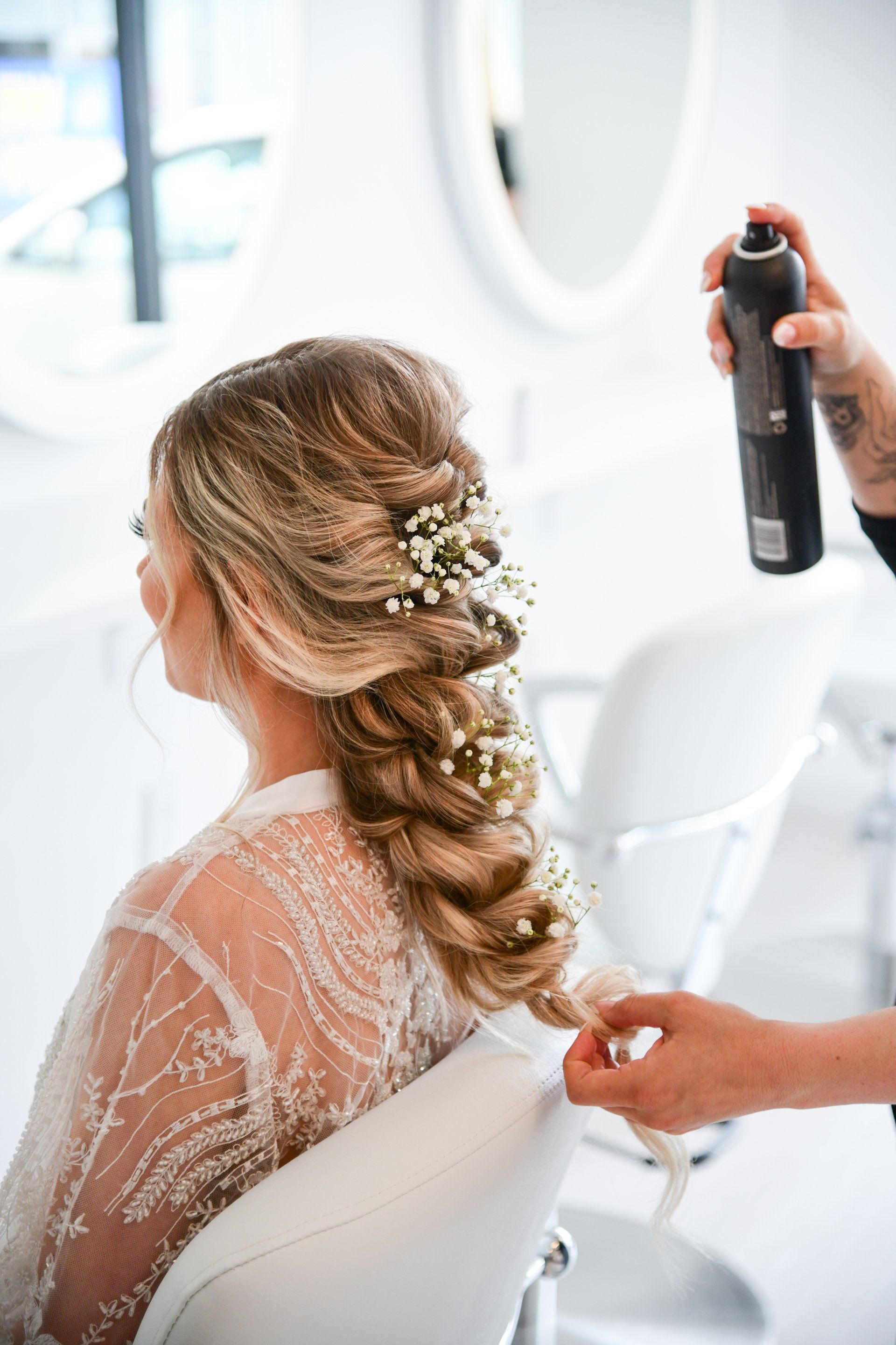 a woman in a wedding dress is getting her hair done by a hairdresser