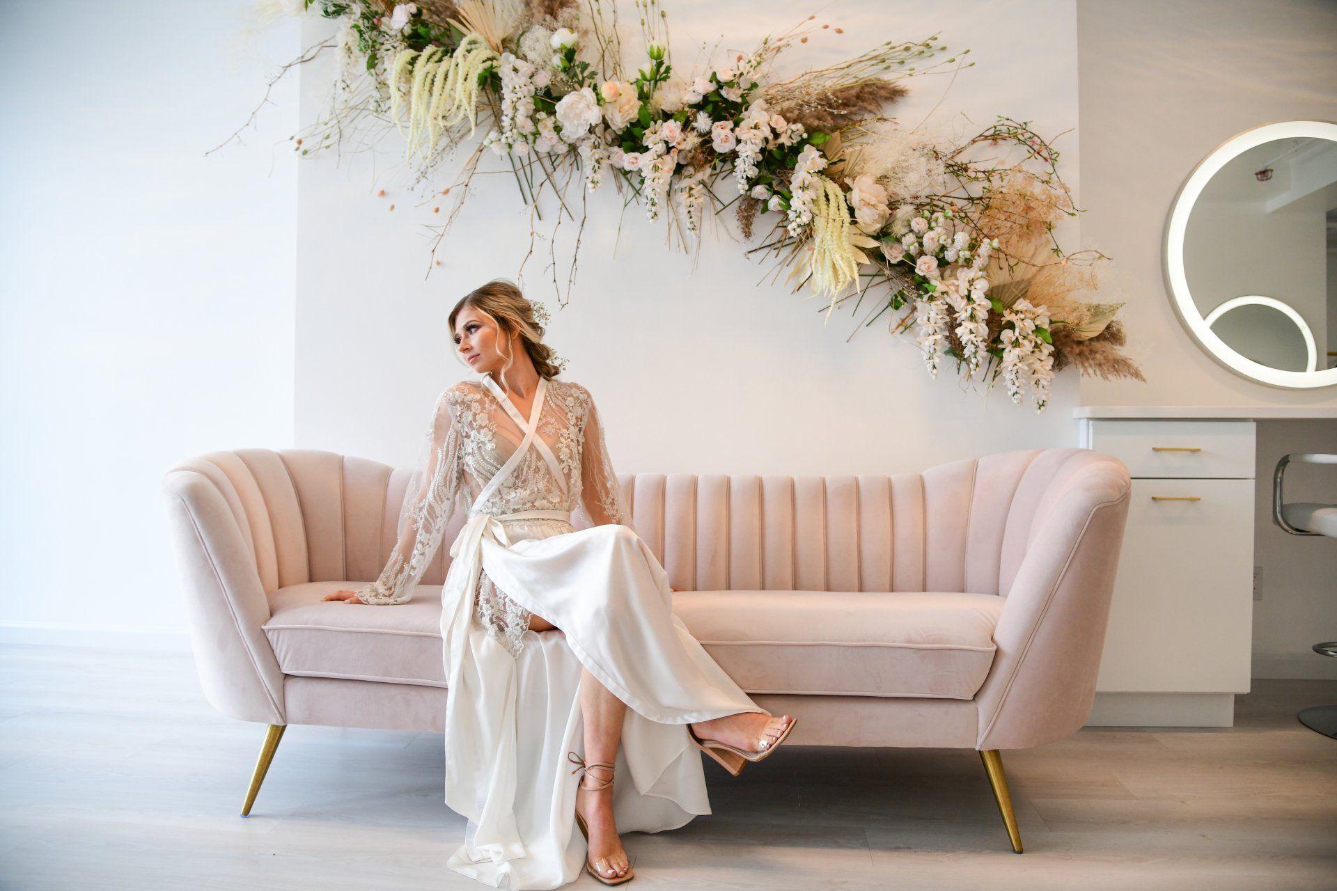 a woman in a wedding dress is sitting on a pink couch