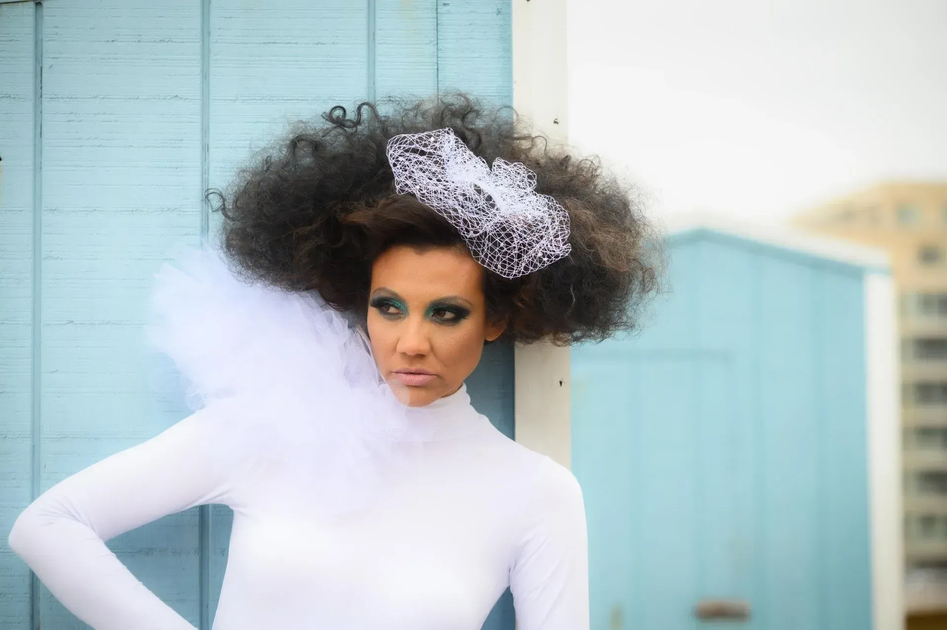 a woman wearing a white dress and a veil is standing in front of a blue building