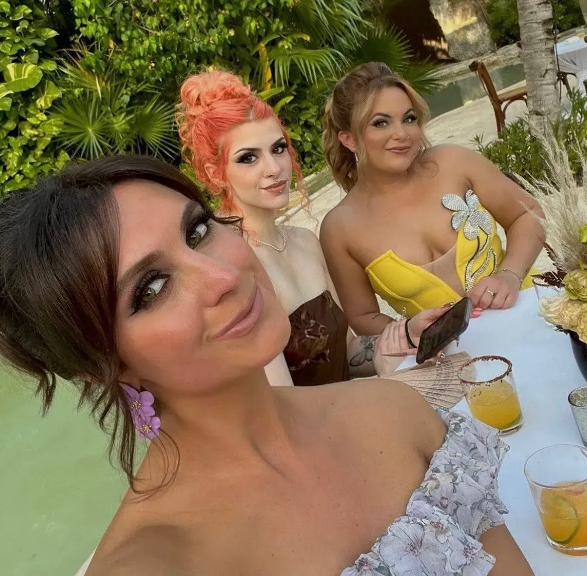 three women are posing for a picture while sitting at a table