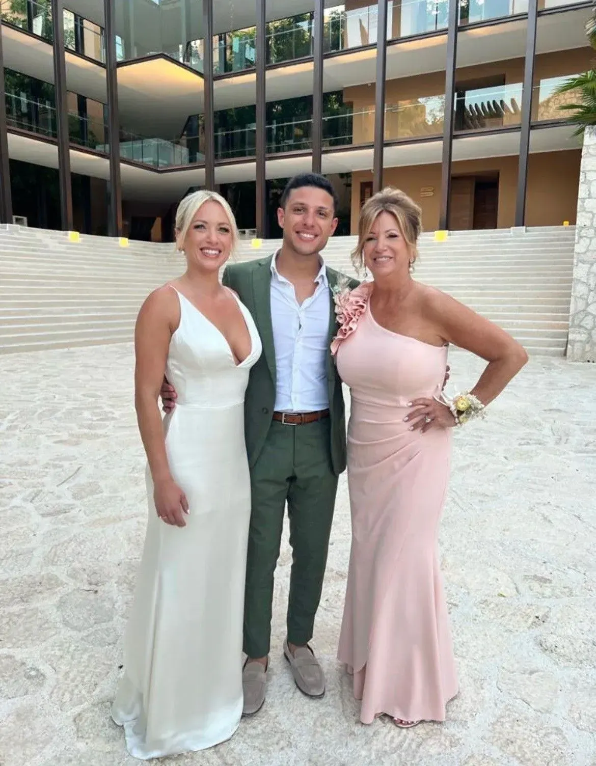 a man and two women are posing for a picture in front of a building