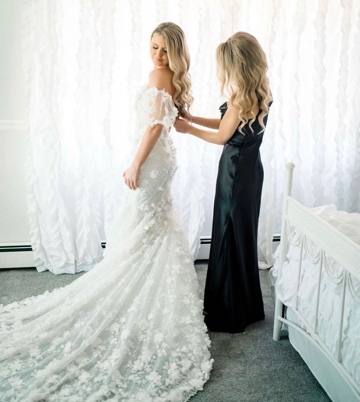 a woman in a black dress is helping a woman in a white dress get ready for her wedding