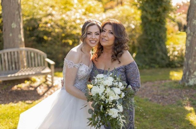 a bride and her mother are posing for a picture in a park