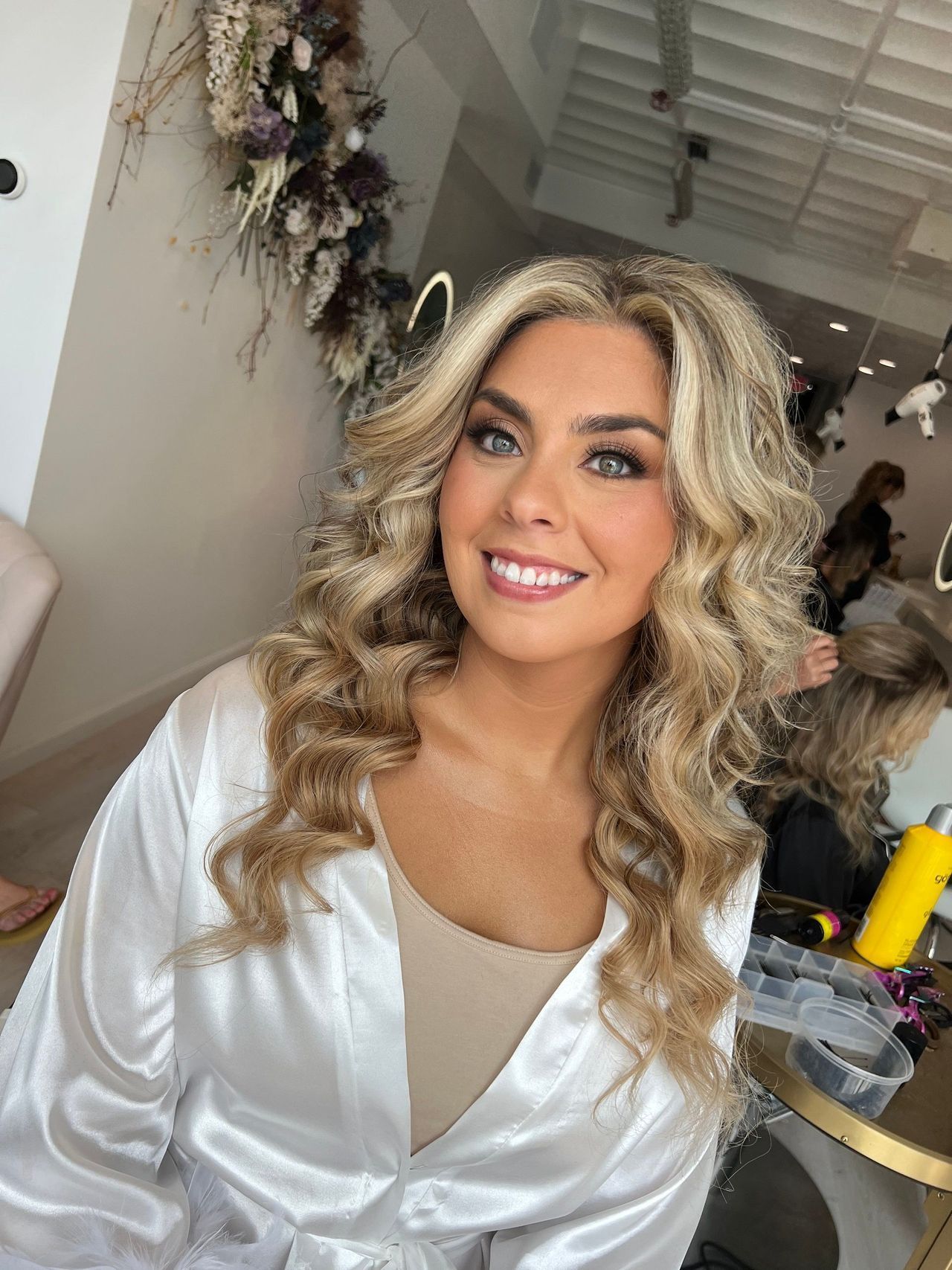 a woman is smiling while getting her hair done in a salon