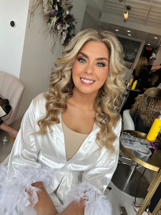 a woman in a white robe is getting her hair done in a salon