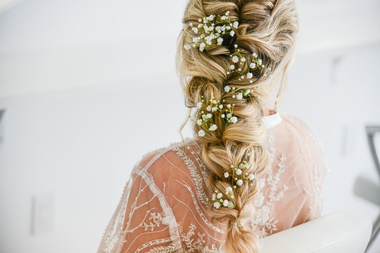 a woman in a wedding dress is wearing a braid with baby 's breath in her hair