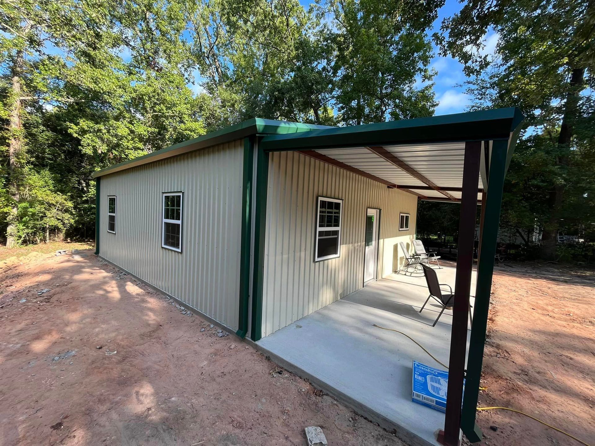 A small house with a covered porch and trees in the background