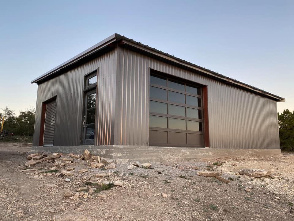 A metal building with a garage door is sitting on top of a dirt hill.