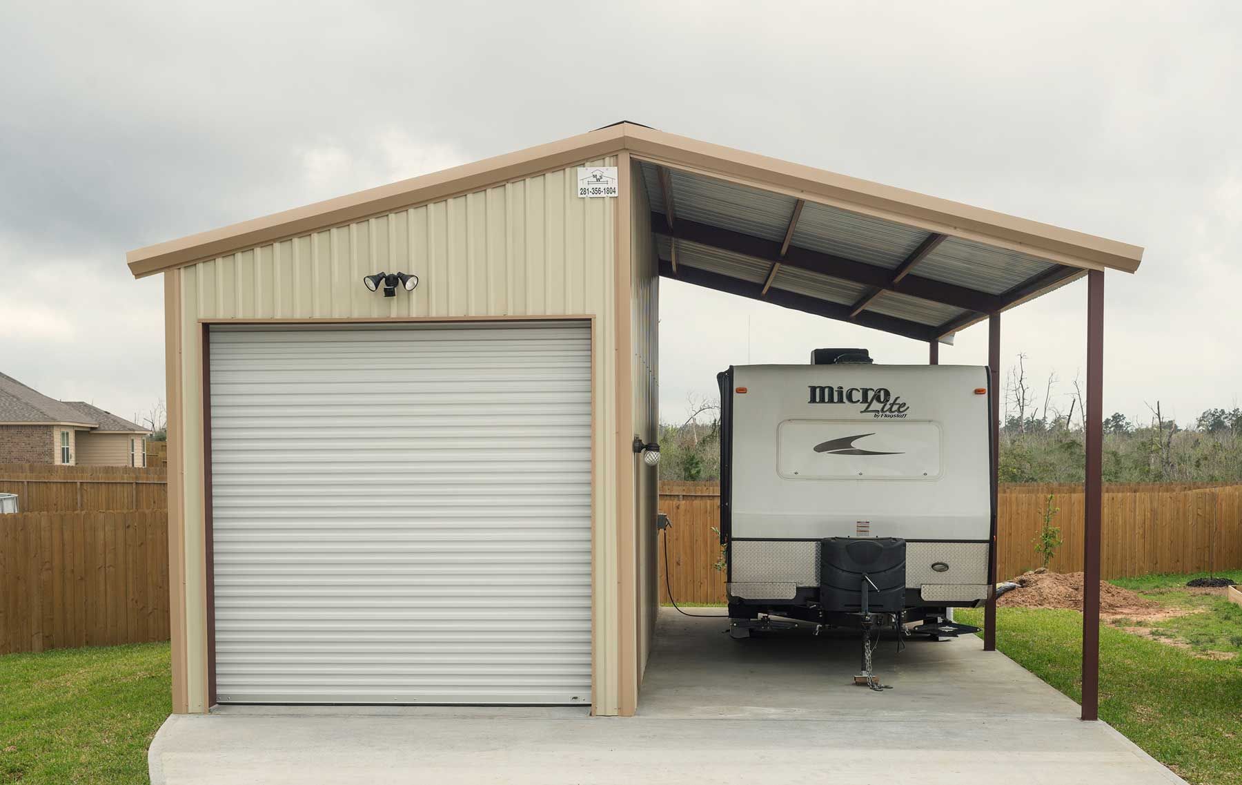 A trailer is parked in a garage under a canopy.