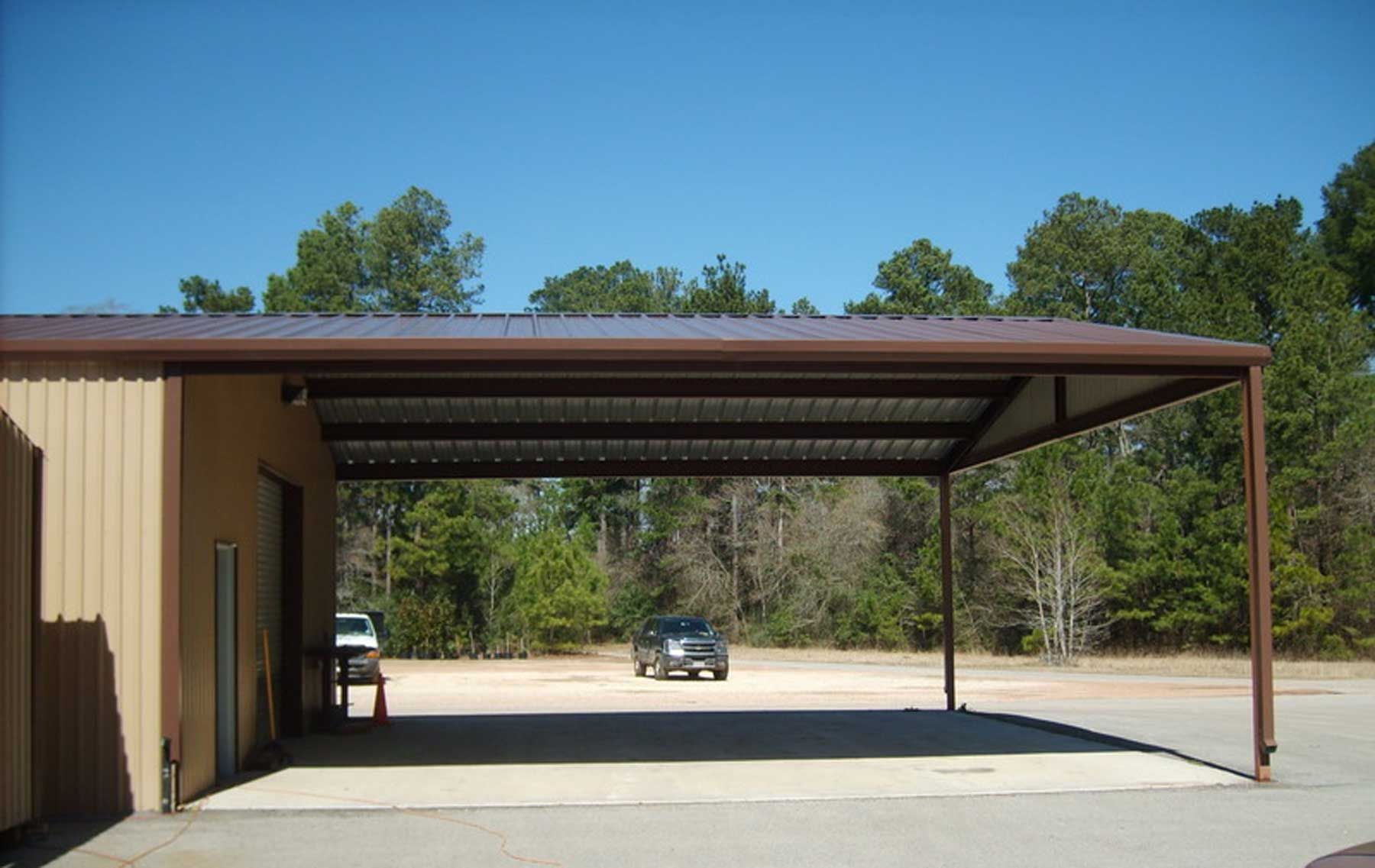 A car is parked under a carport in front of a building