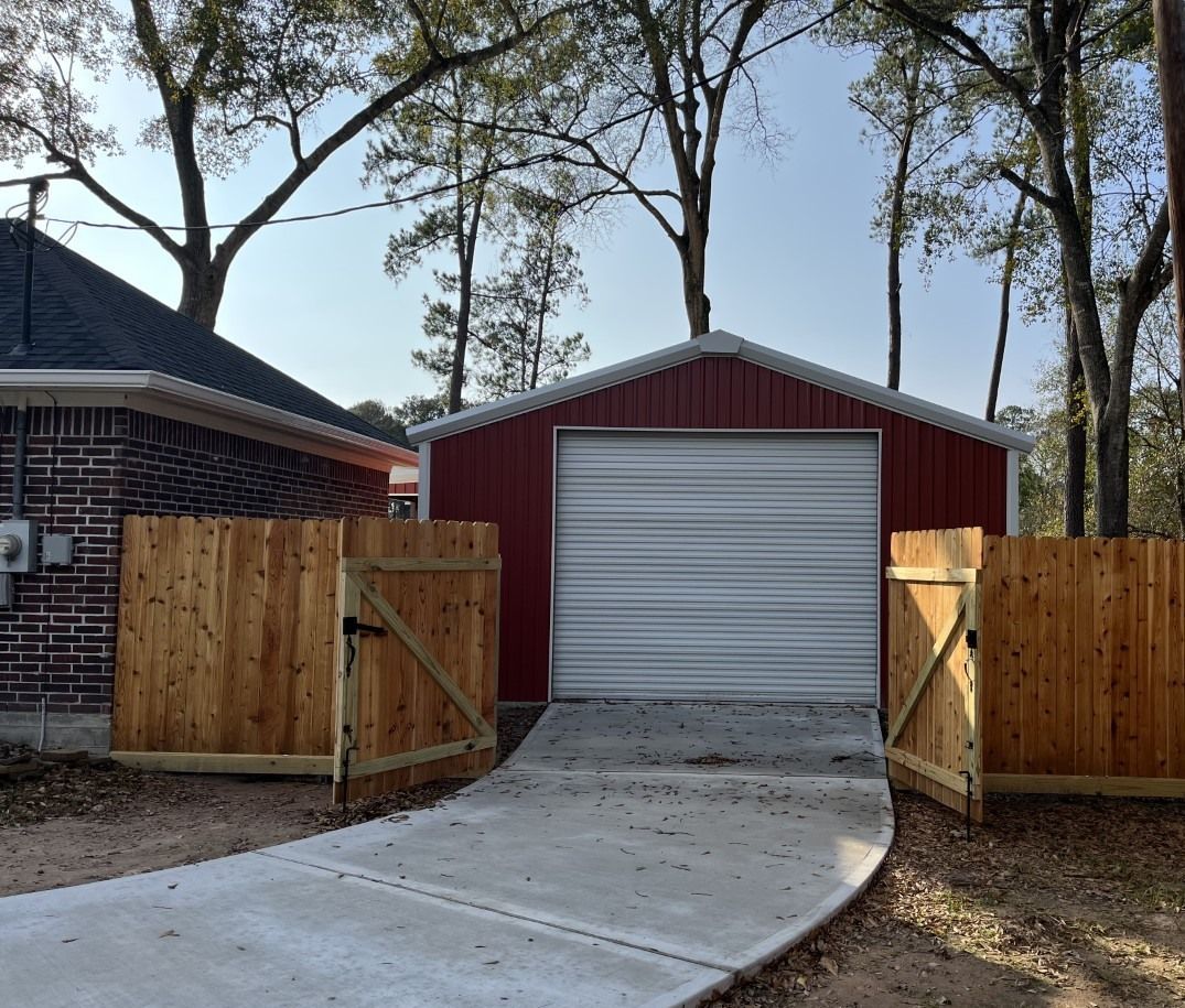 A red garage with a white door and a wooden fence around it