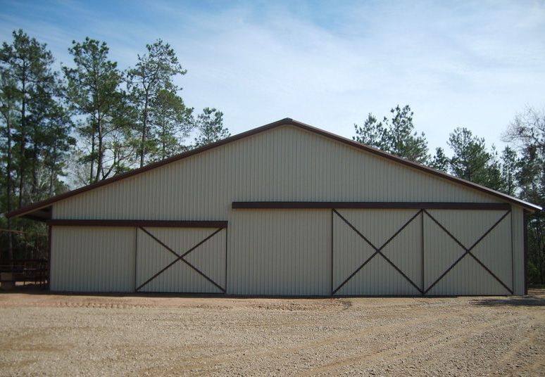 A large barn with sliding doors in a gravel area