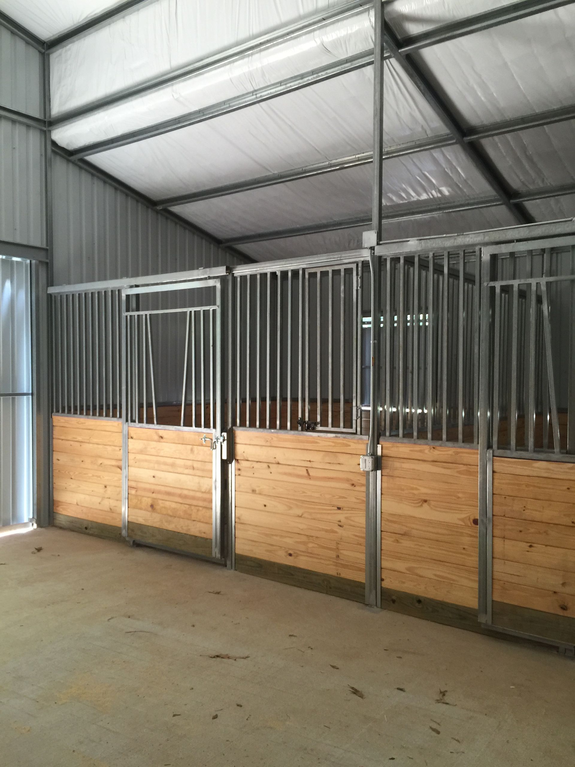 A horse stable with wooden walls and metal fences