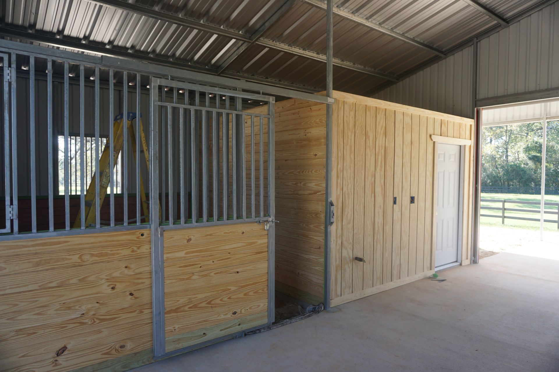 A horse stable with wooden walls and a metal roof