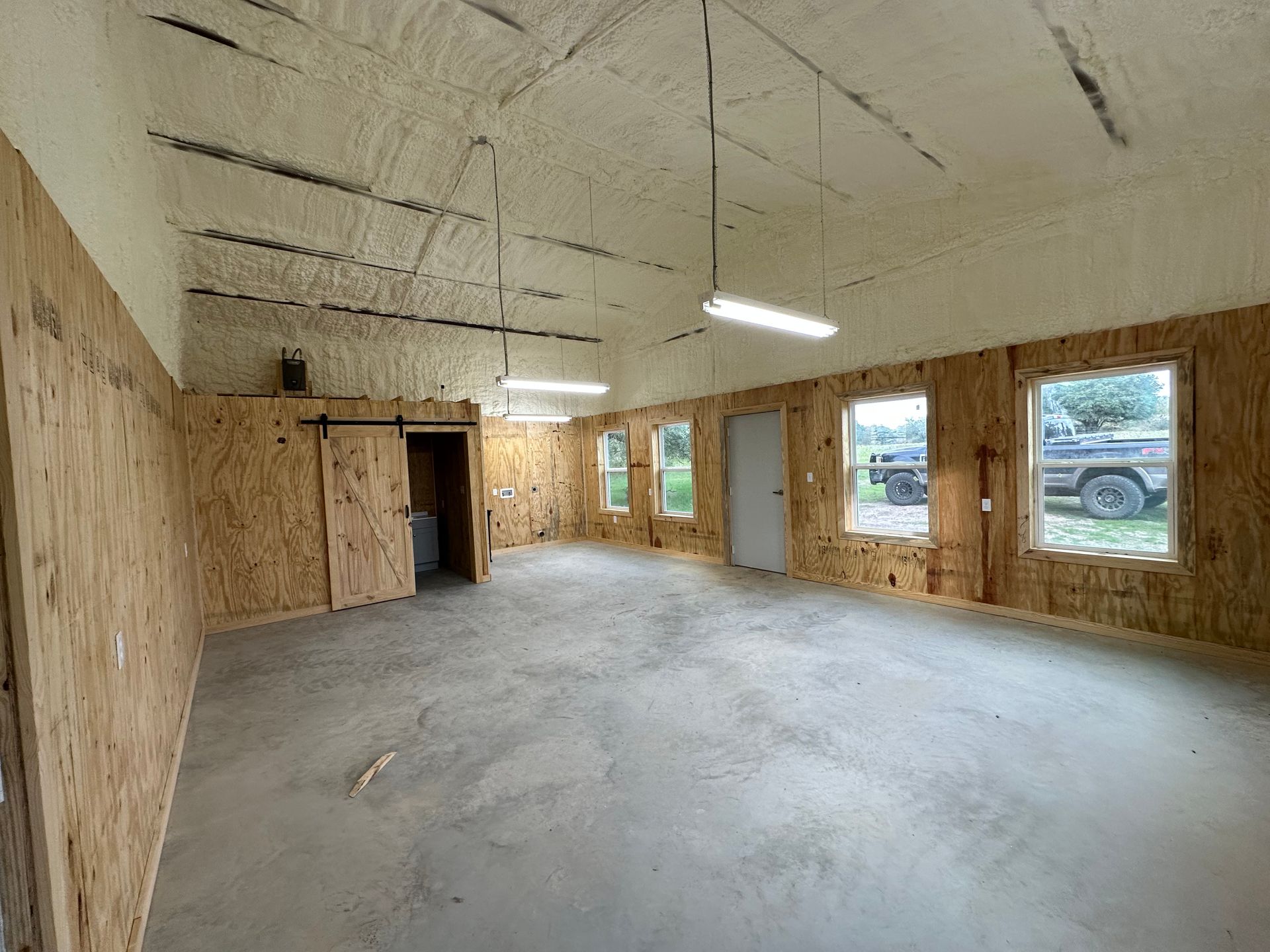 A large empty room with a lot of windows and a truck parked in the background.