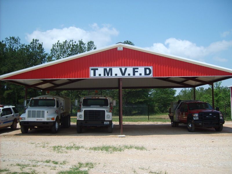 Three trucks are parked under a red roof.