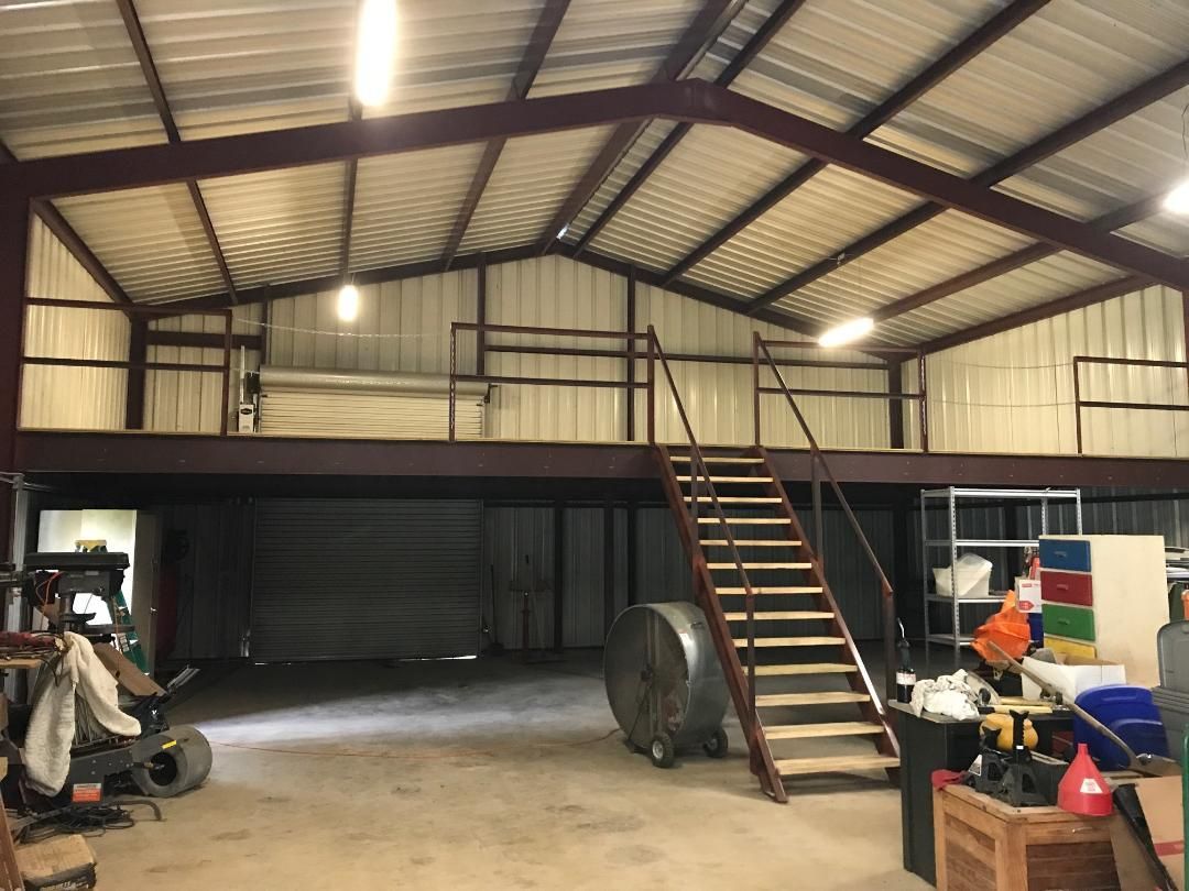 A large metal building with stairs leading up to a loft