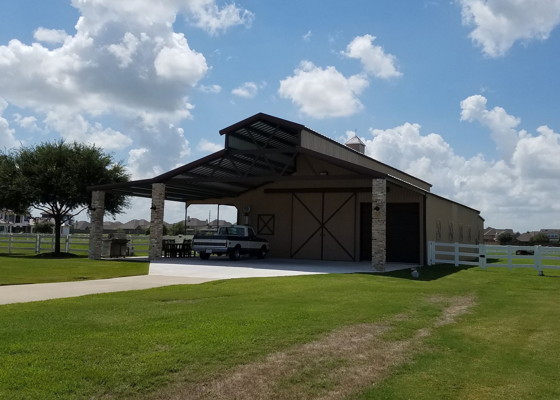 A barn with a covered area and a truck parked in front of it