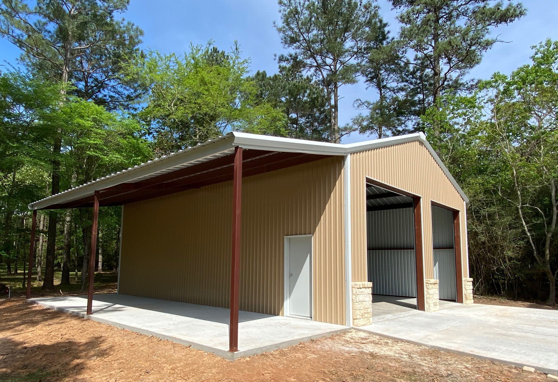 A large metal building with a covered porch and trees in the background.