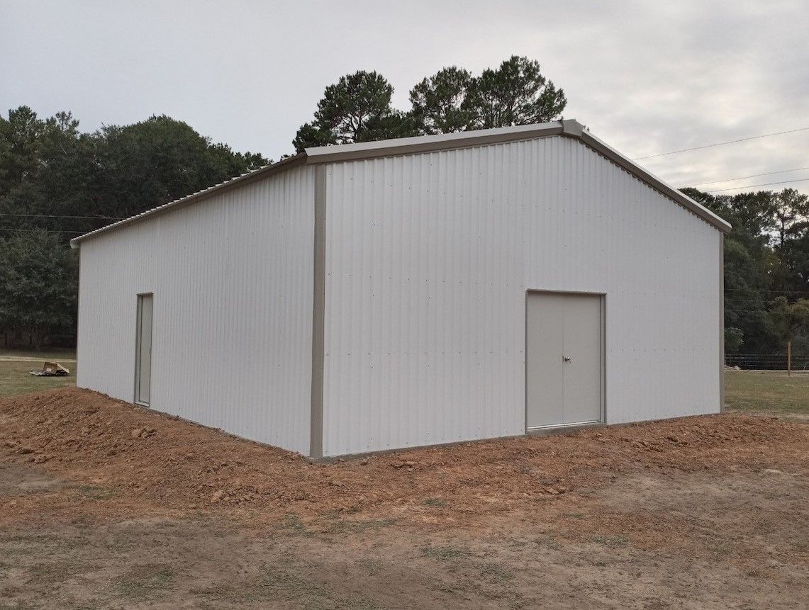 A large white building is sitting in the middle of a field.