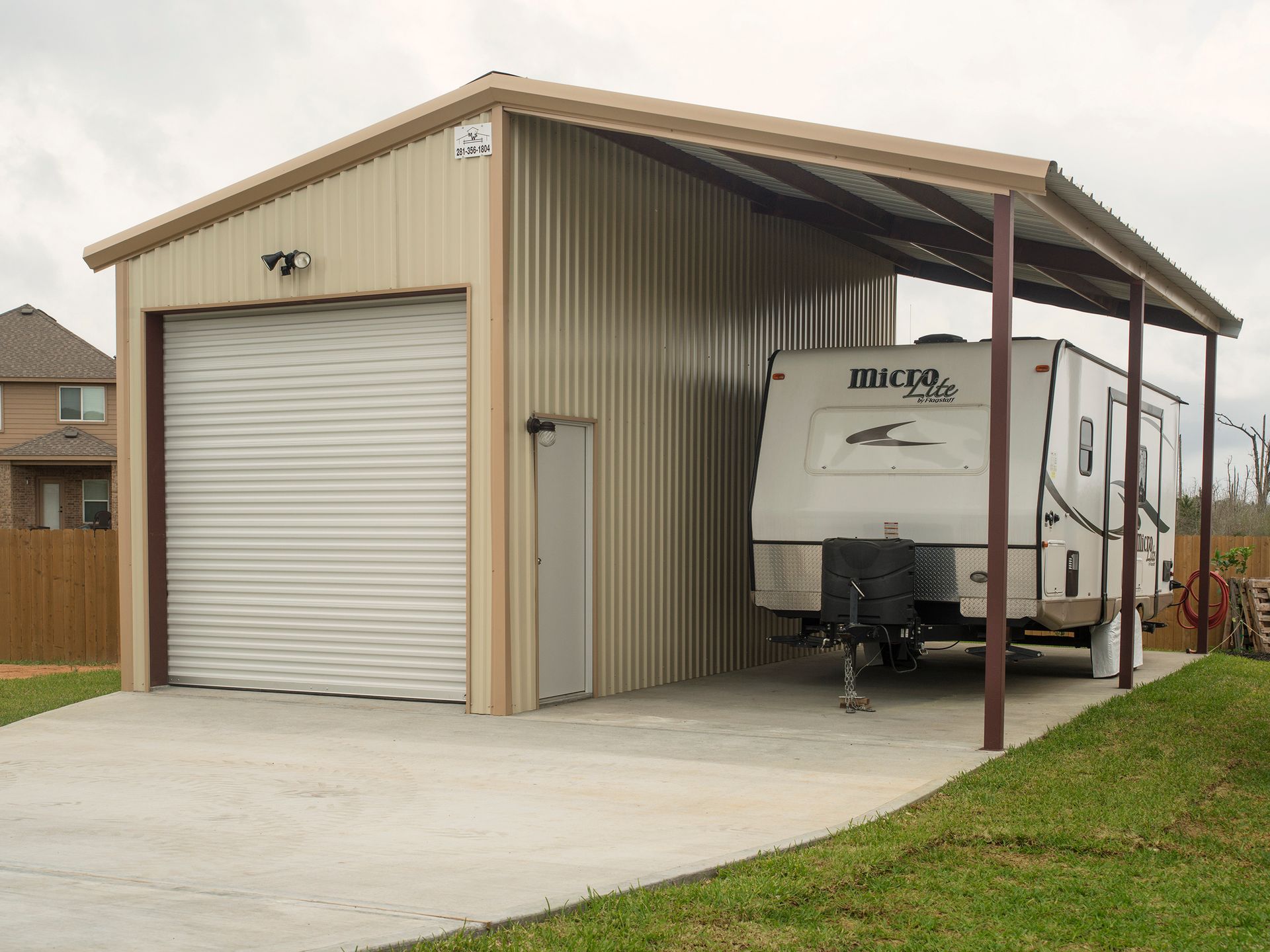 A trailer is parked under a covered garage.