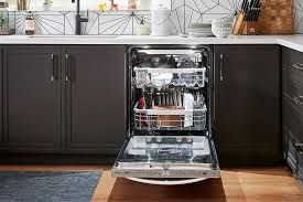 Open dishwasher in a kitchen with dark cabinets and a stainless steel interior