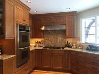Warm wood kitchen with stainless oven, granite counters, and a window over the sink