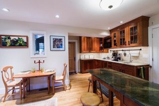 Bright kitchen and dining area with wooden cabinets, green countertops, and a small table by the window.