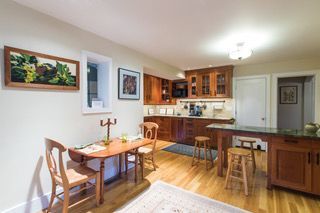 Bright kitchen and dining area with wooden cabinets, table, stools, and wall art