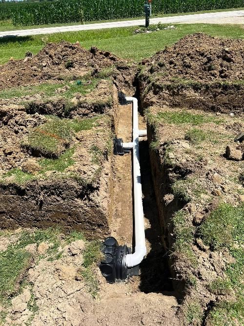 A pipe is being installed in a trench in the dirt.