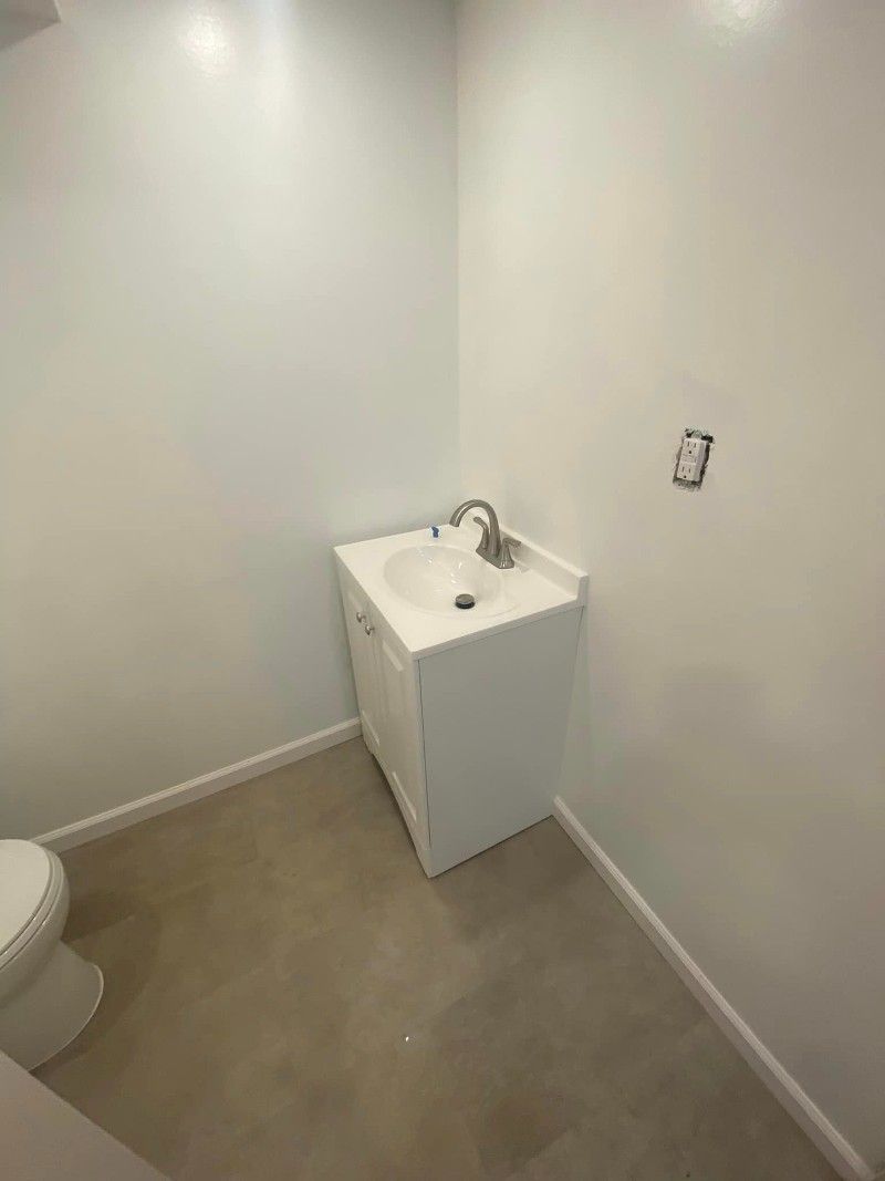 A bathroom with a sink , toilet and white walls.