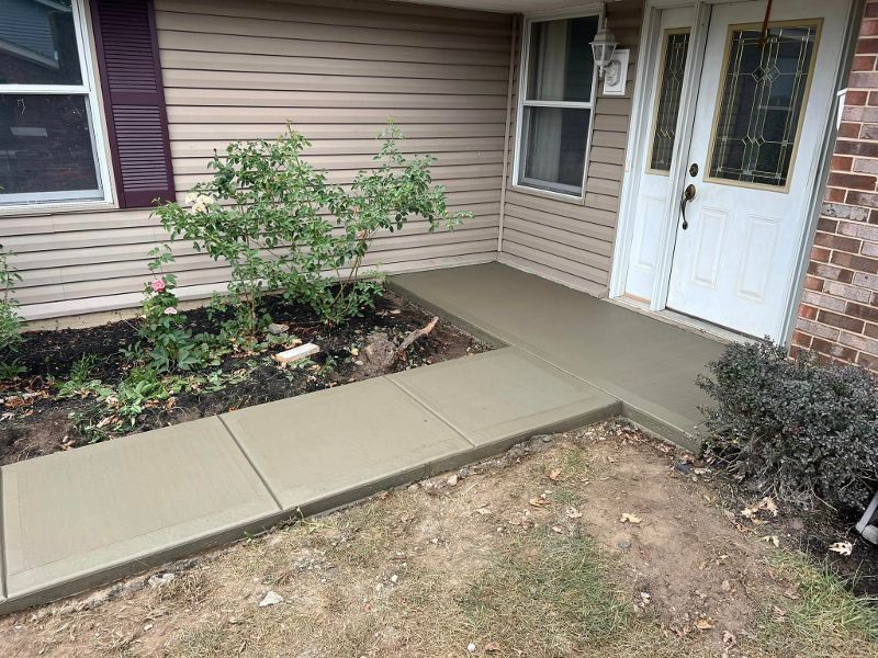 A concrete walkway leading to the front door of a house.