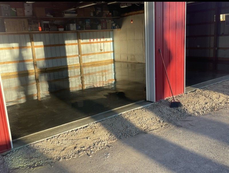 A garage with a red door and a broom in front of it.