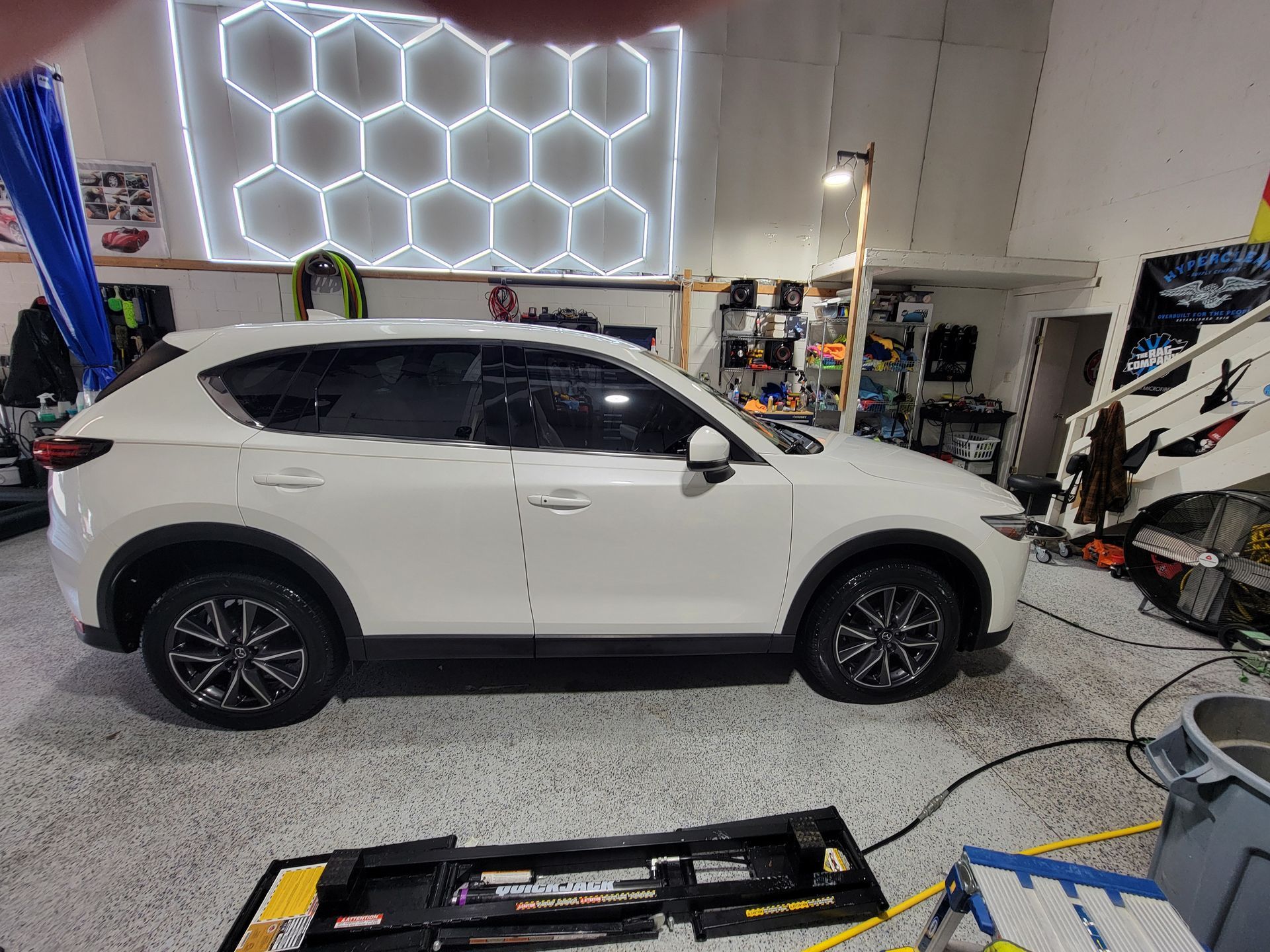 A white car is parked in a garage next to a neon sign.