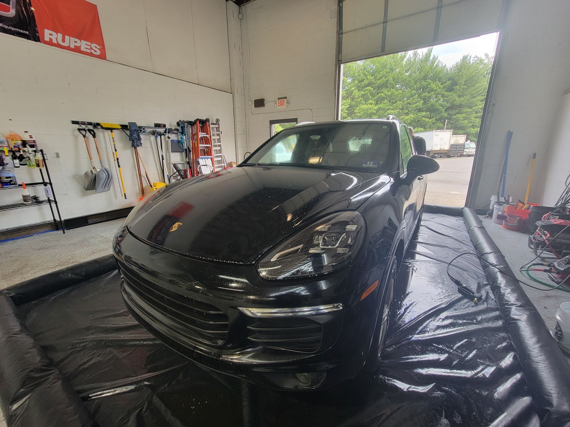 A black porsche cayenne is parked in a garage.