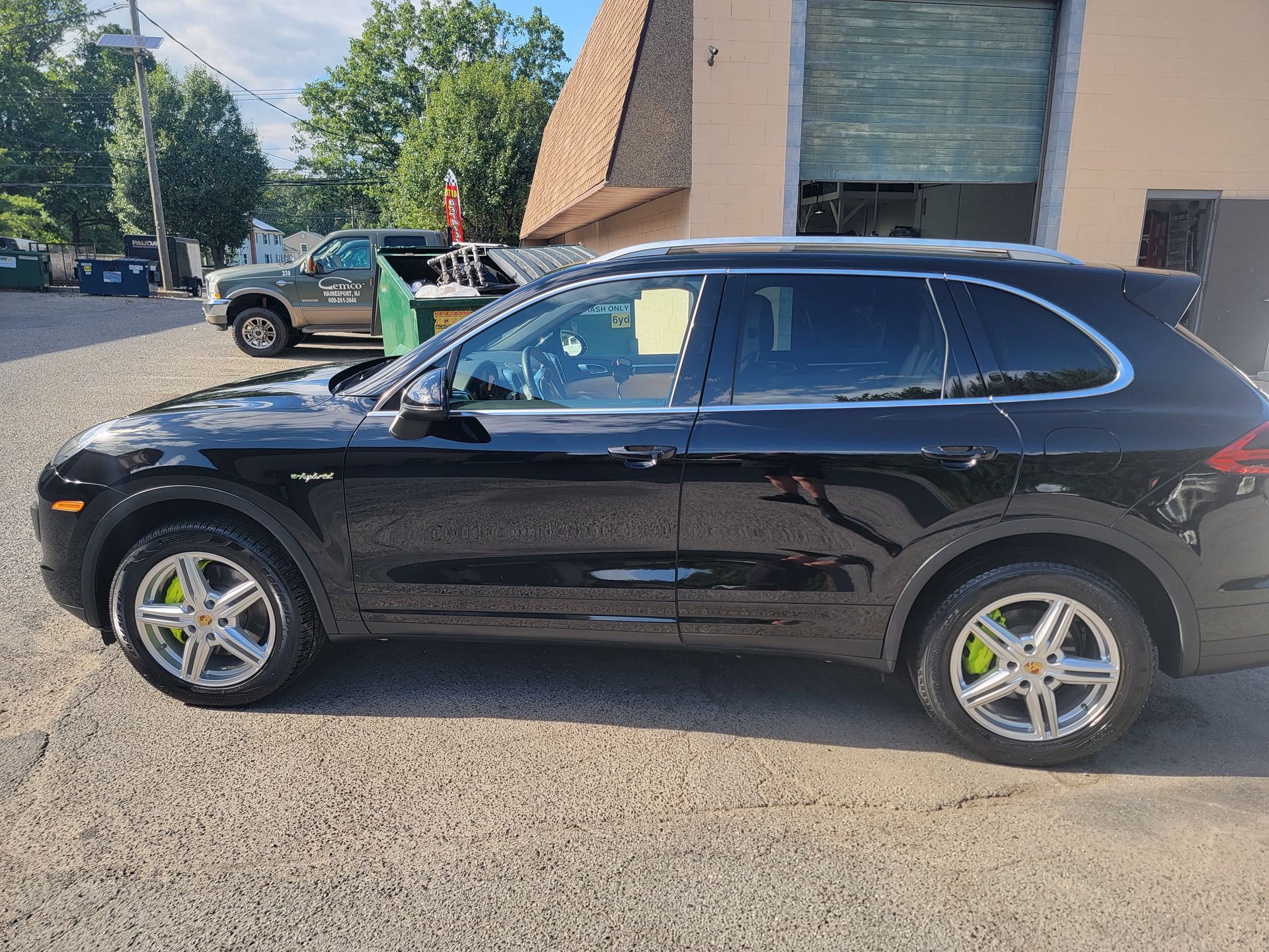 A black porsche cayenne is parked in front of a building.
