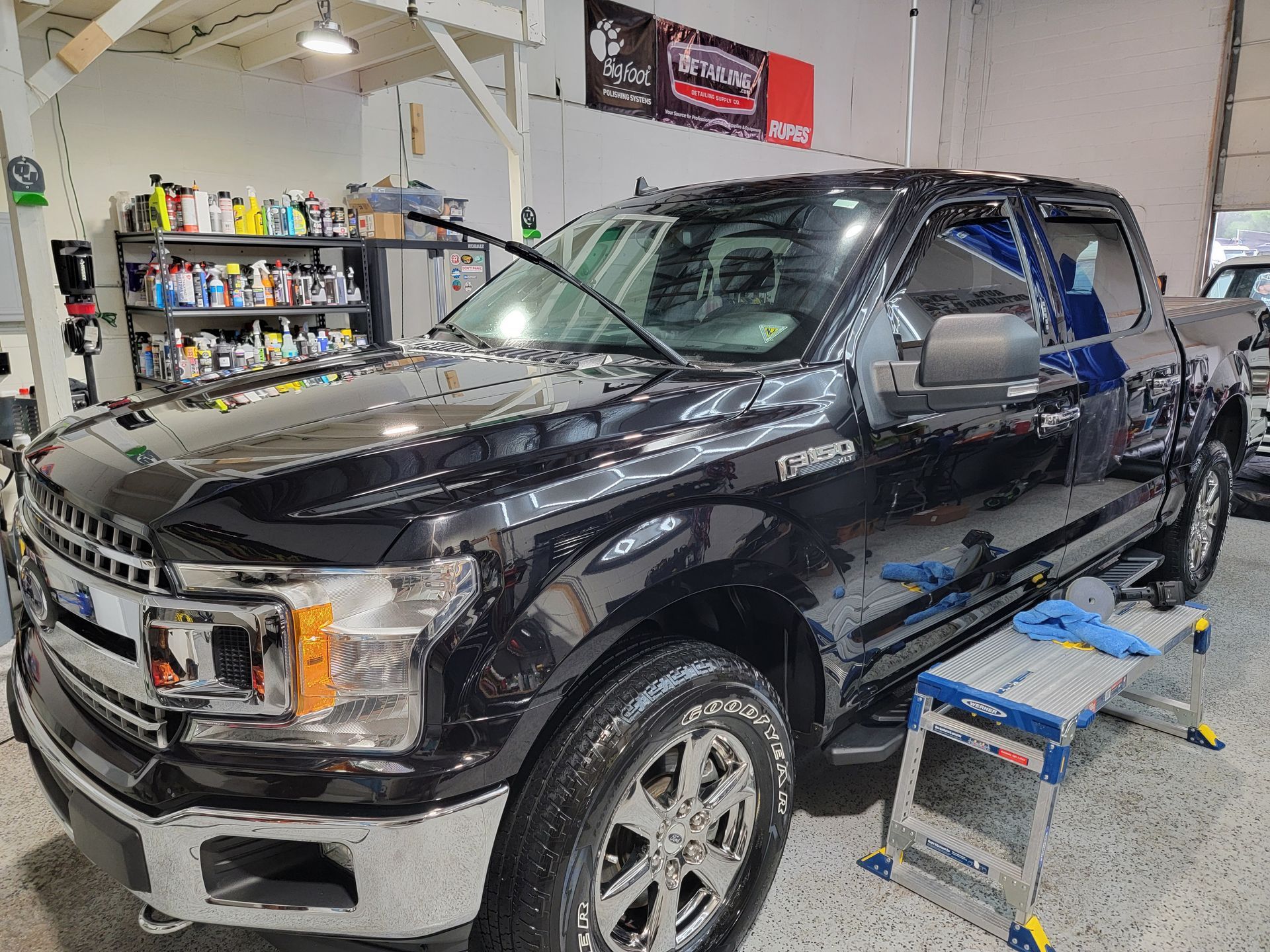 A black ford f150 is sitting on a stool in a garage.
