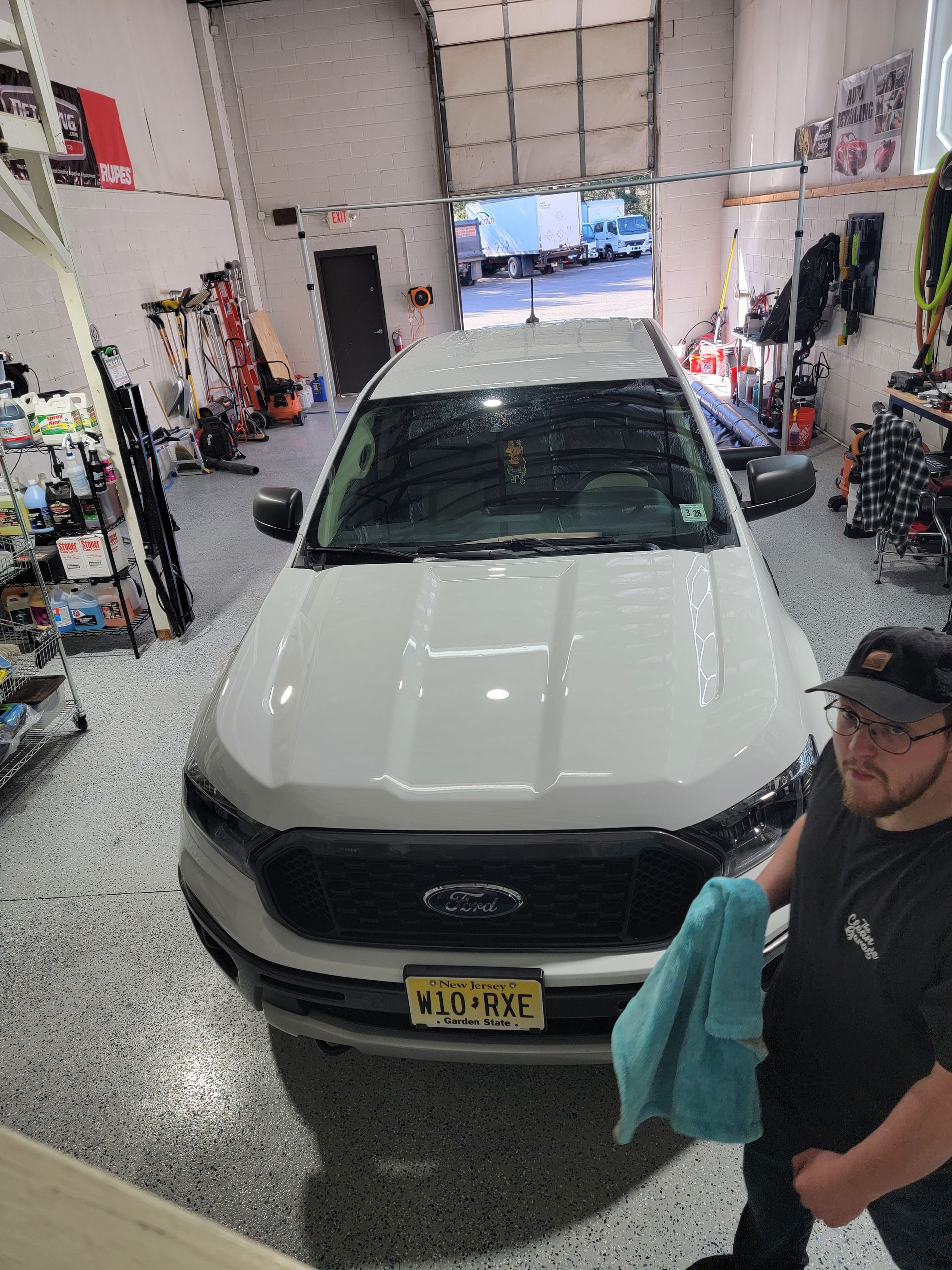A man is standing in front of a white truck in a garage.
