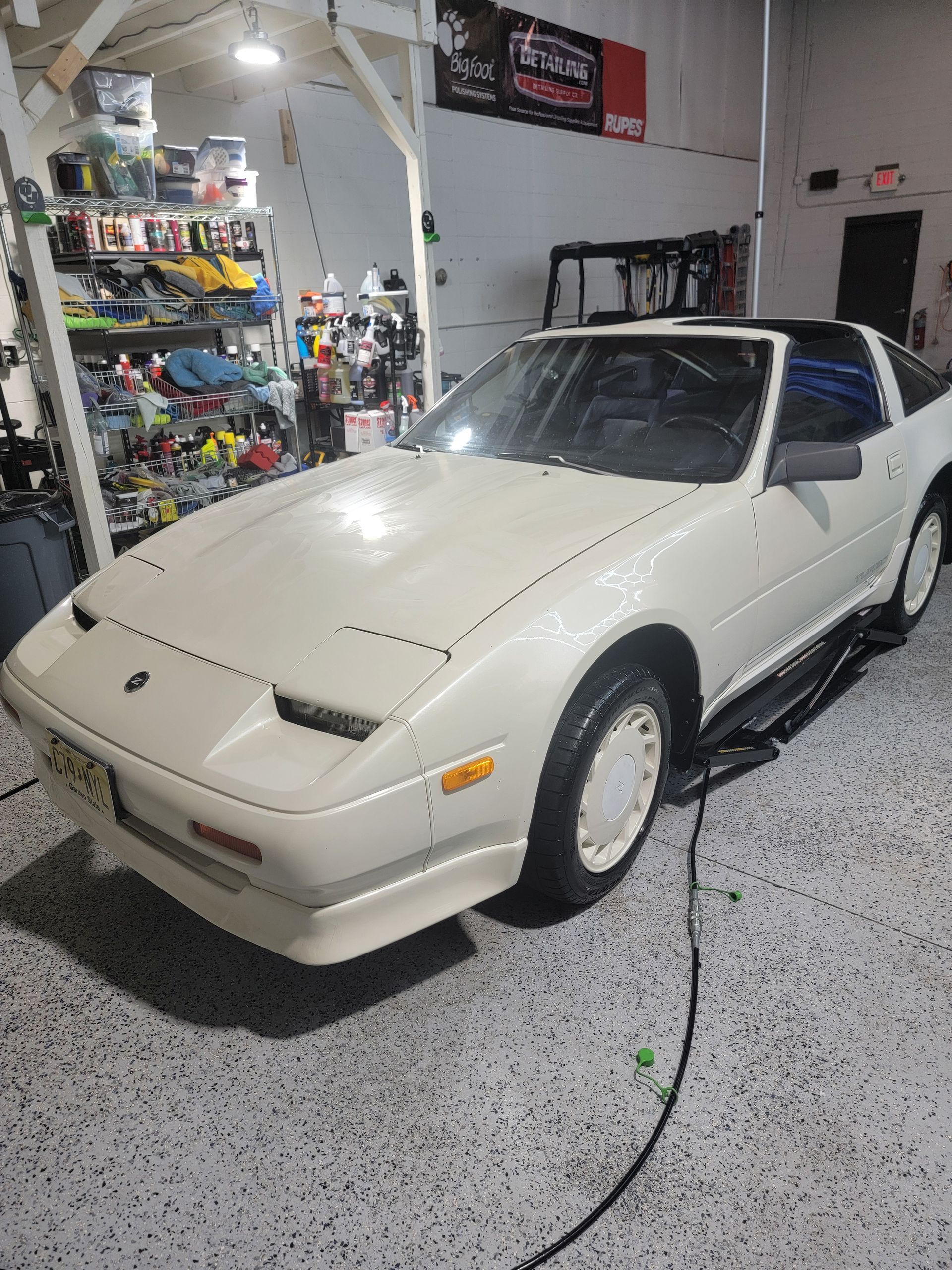 A white sports car is parked in a garage.