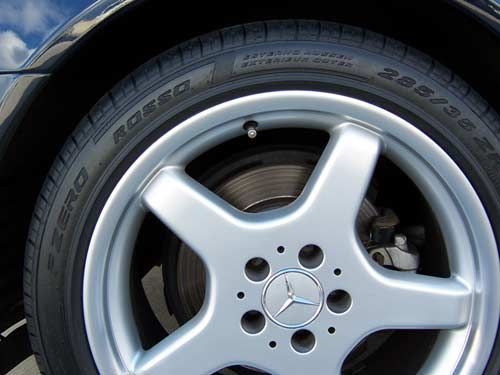 Close-up of a car tire and silver rim with a Mercedes-Benz logo.
