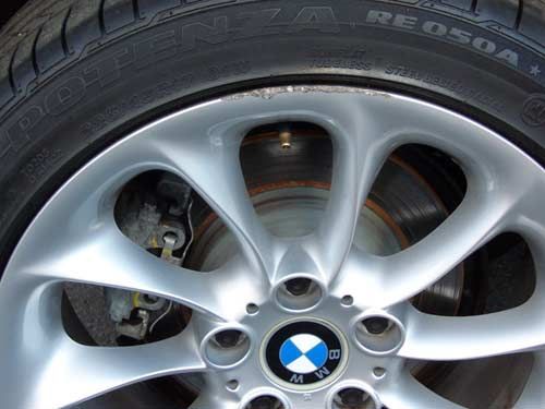 Silver BMW wheel with a blue and white logo, a tire, and a brake disc.