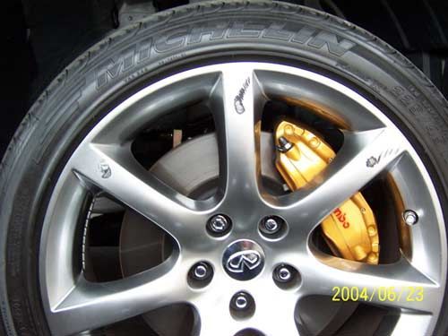 Silver car wheel with gold Brembo brake caliper.