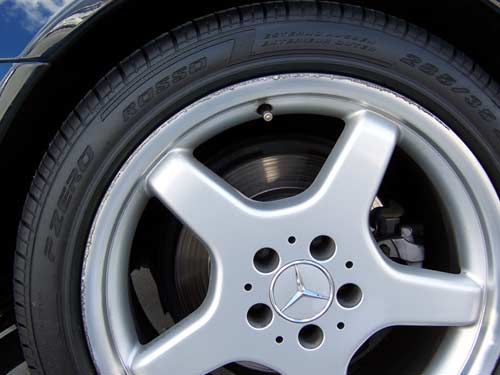 Silver car wheel with a black tire and a Mercedes-Benz logo.