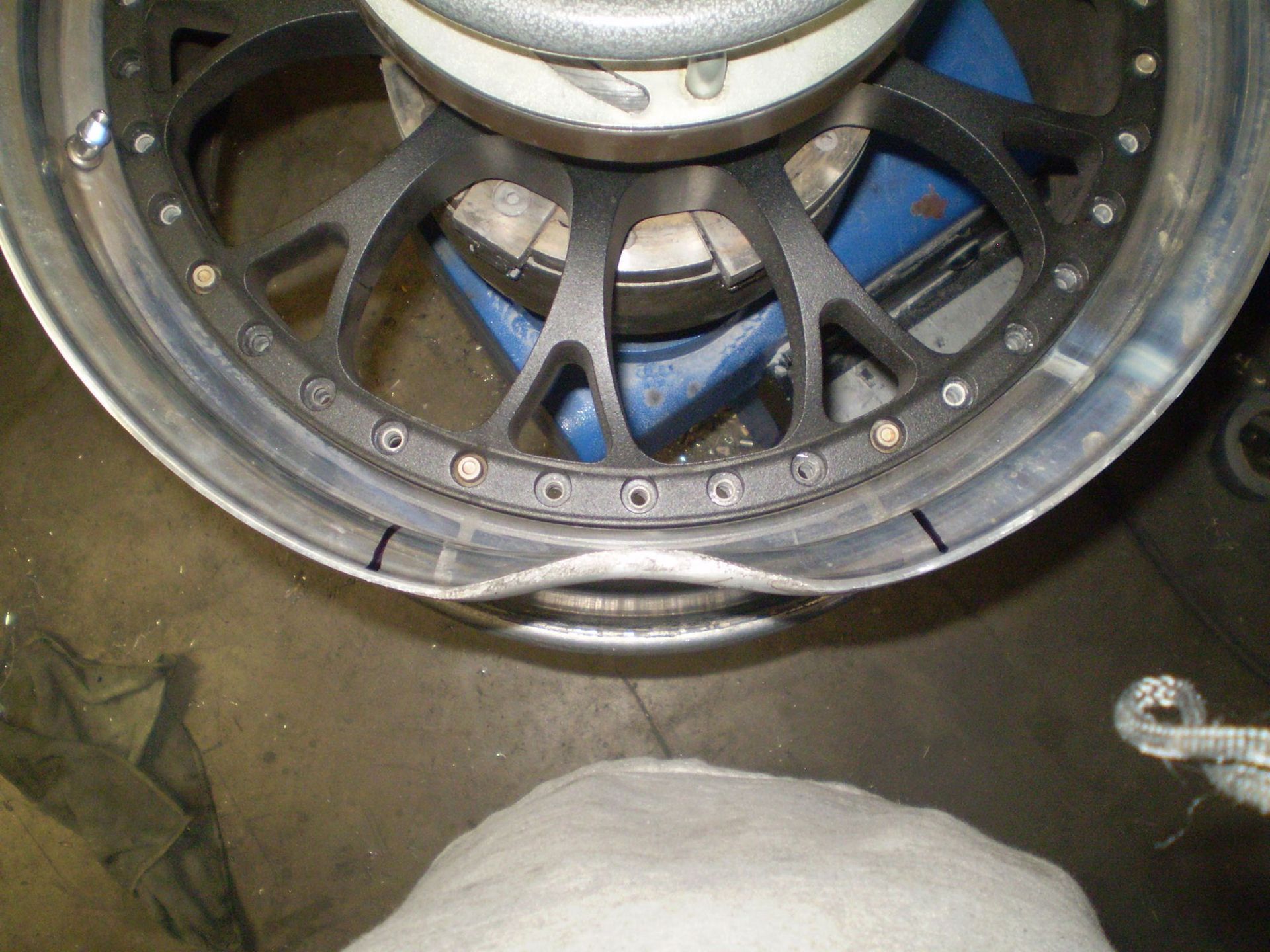 Car wheel being machined on a lathe, with metal shavings visible in a workshop setting.