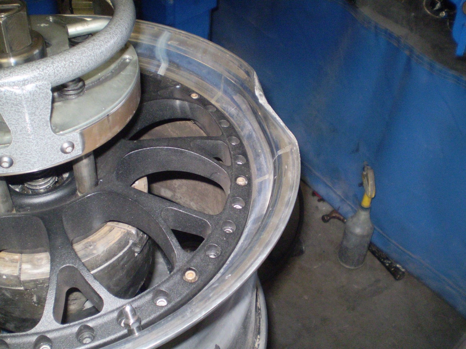 Damaged car rim being repaired by a machine in a workshop setting.