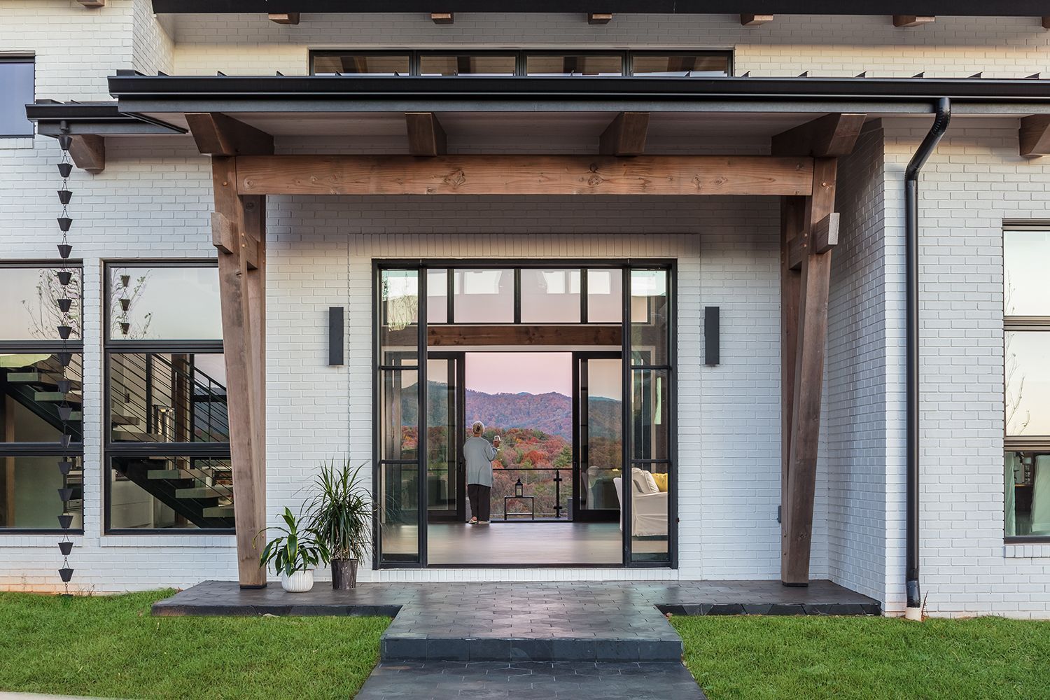 The front of a white house with a large porch and sliding glass doors.